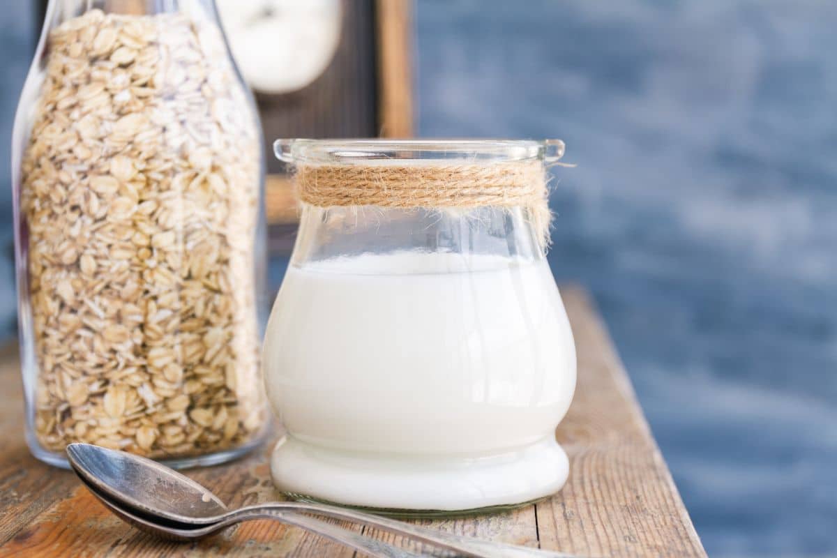 Jumbo rolled oats in a glass bottle, with a small jug of oat milk.
