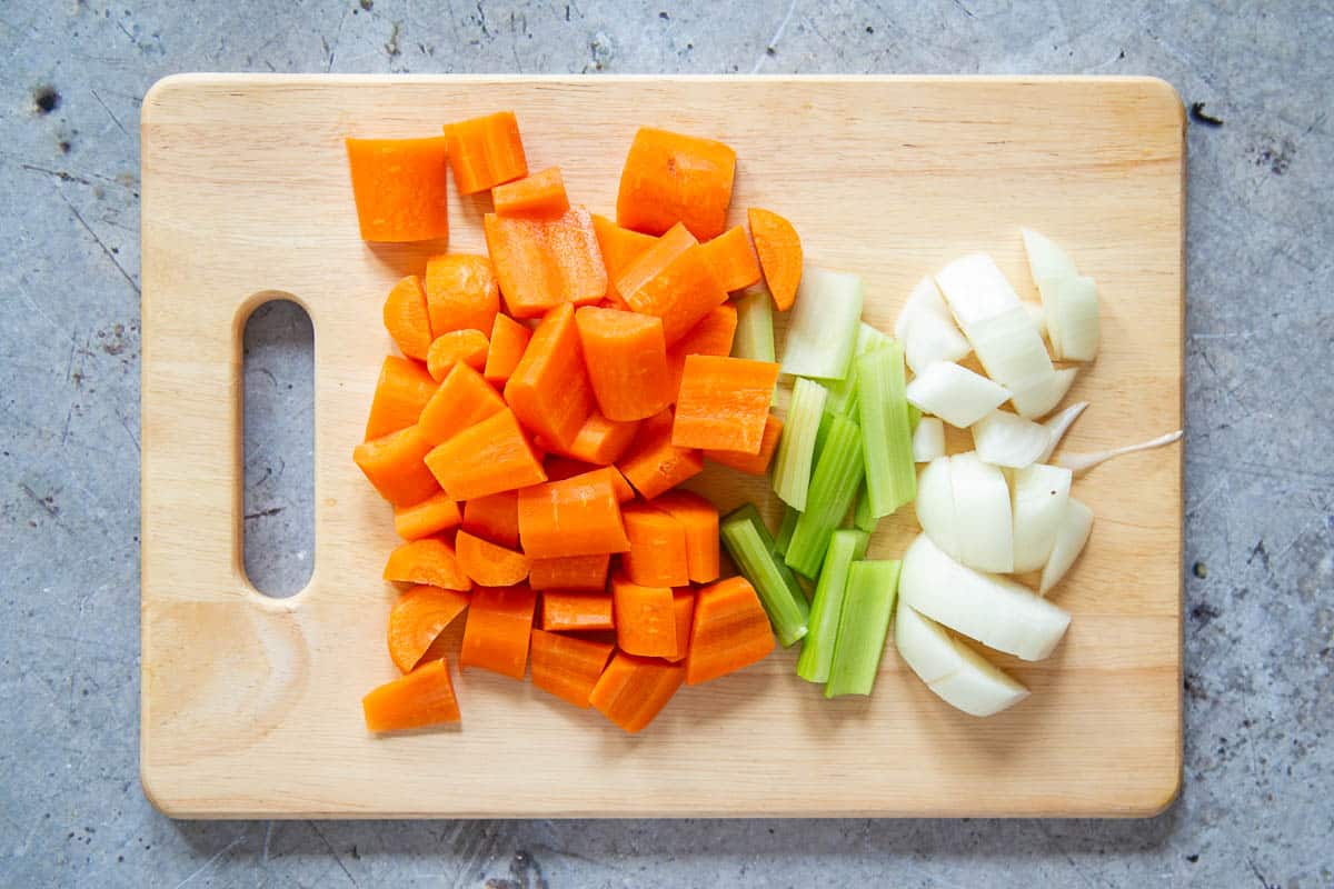 a board with prepared chopped carrots, celery and onion