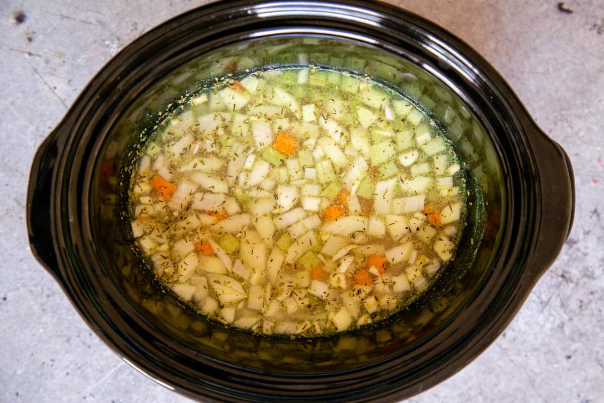 The prepared onion, carrot, celery and garlic are placed in the pot with the chicken, seasoning and stock, ready to cook.