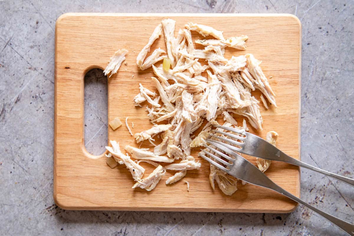 Breaking up the cooked chicken with a pair of forks is easier than cutting with a knive.