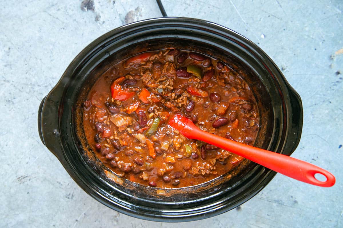 The chili in the slow cooker pot, ready to serve. It is rich and dark and tempting.