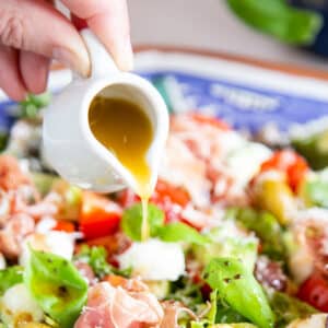 Pouring Italian dressing over a mixed salad.