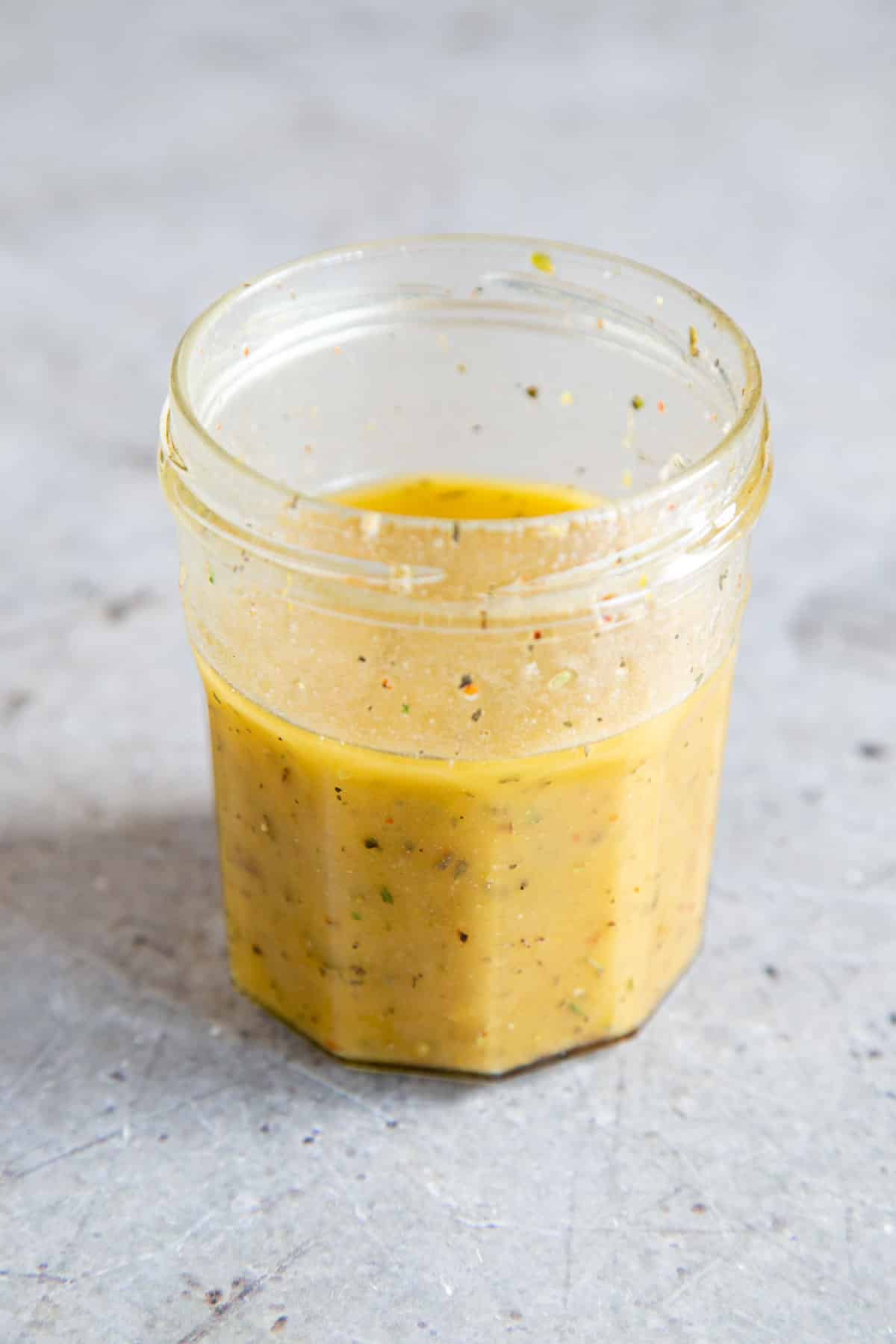 The emulsified dressing in a jar, golden in colour and flecked with chilli flake and herbs.