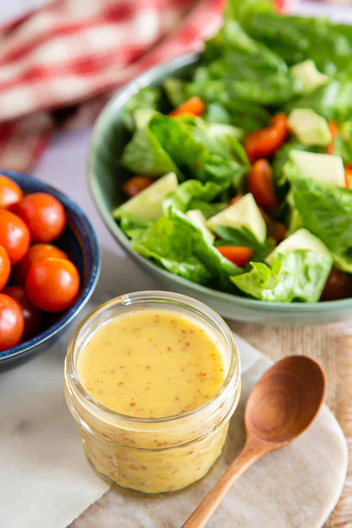 Honey mustard dressing served in a jar with a fresh mixed salad.