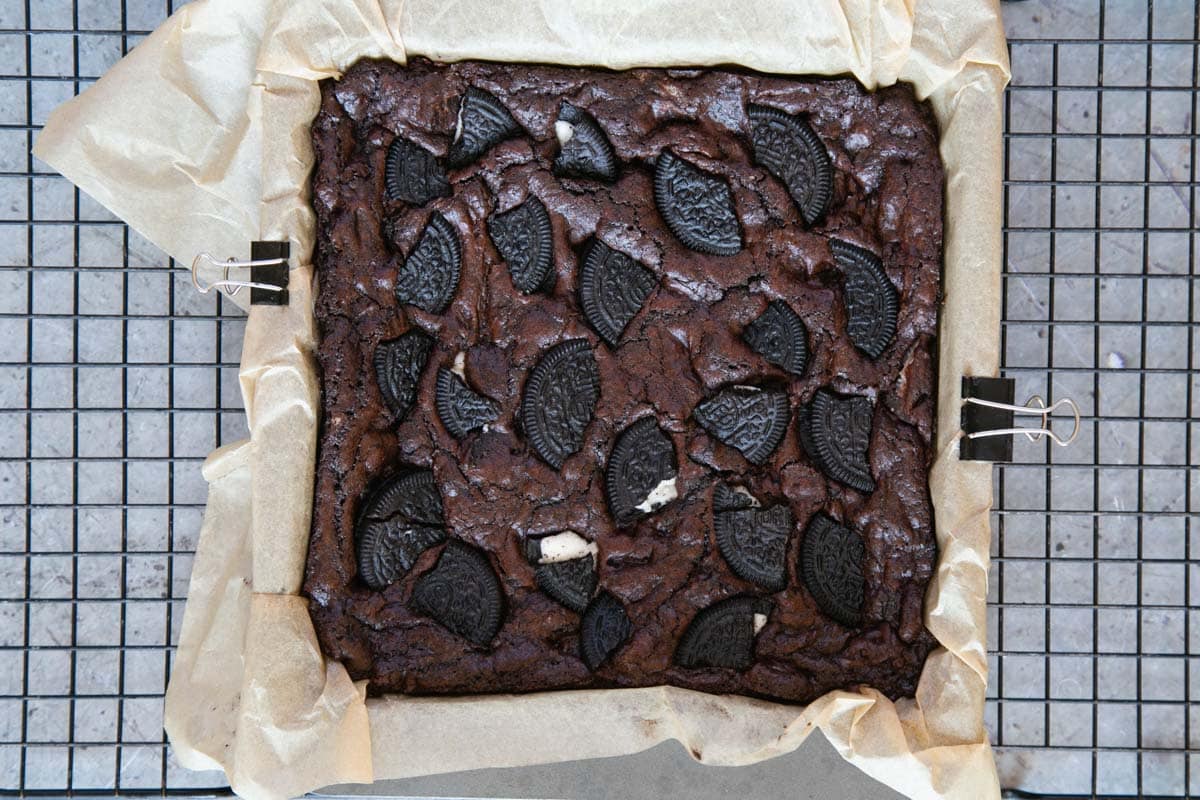 The finished bake, still in the pan, the very dark brown of the brownie studded with pieces of Oreo cookie