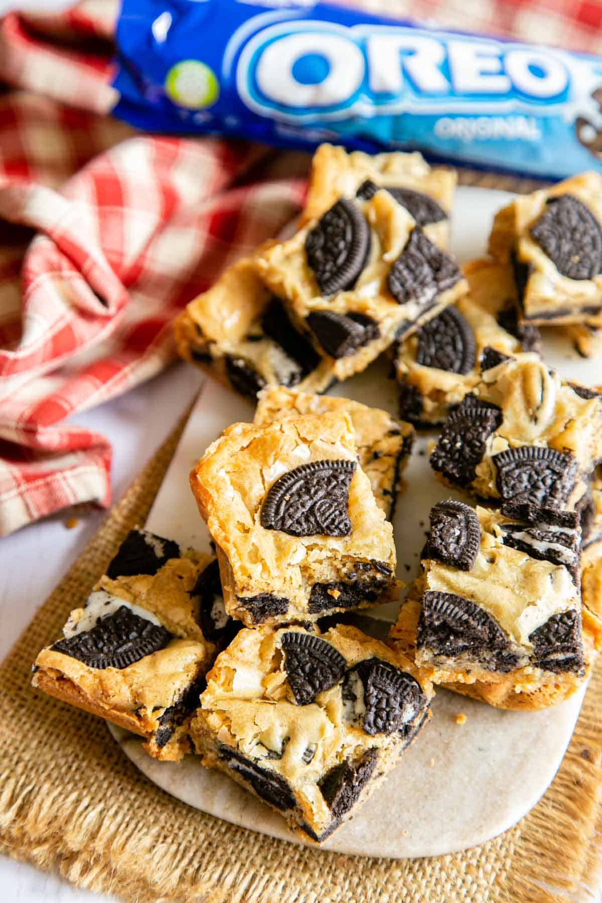 Cookies and cream blondies on a serving board, the dark cocoa biscuits contrasting with the golden blondie crust.