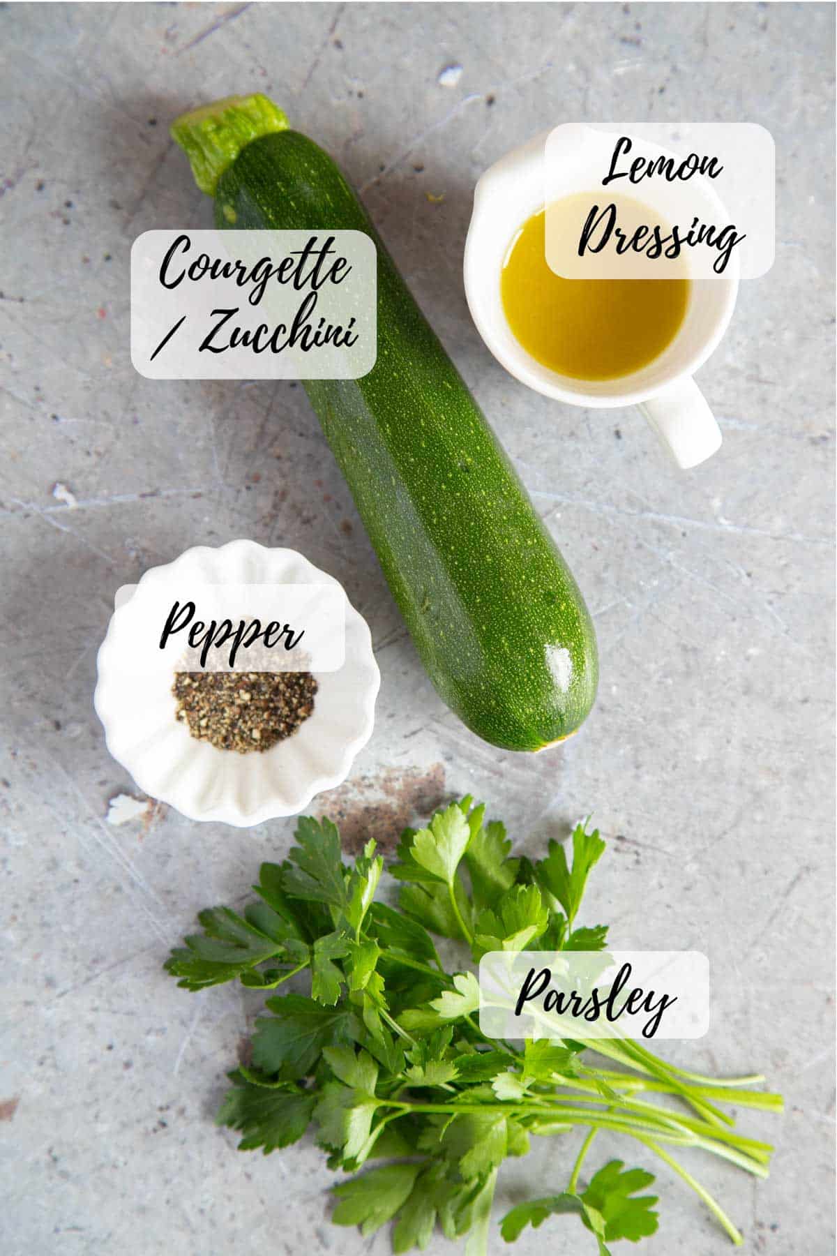 Ingredients for courgette salad: courgettes, lemon dressing, fresh parsley and black pepper.