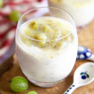 A delicious glass of gooseberry fool, topped with extra gooseberries.