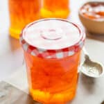 A golden jar of pink grapefruit marmalade, with light shining through.