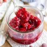 Spooning jewel-like cranberry compote from a glass serving dish.