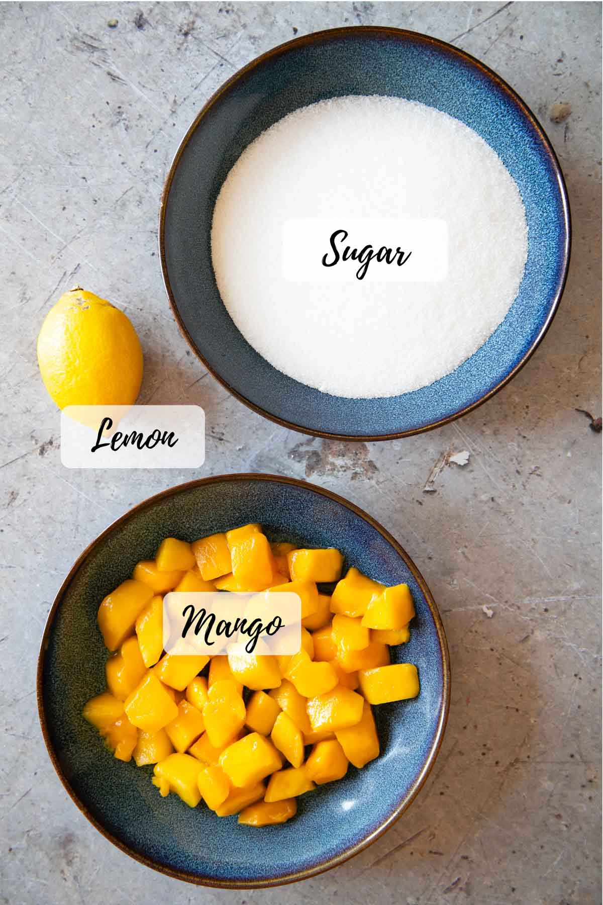 The ingredients: granulated white sugar, chopped frozen mango, and a lemon.