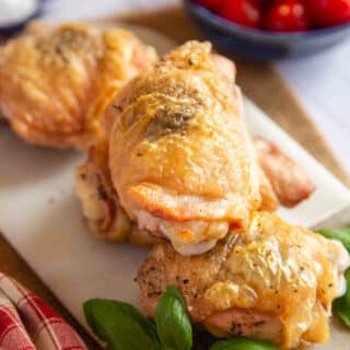 Baked Italian chicken thighs on a serving platter, the skins golden and crispy, the meat juicy.