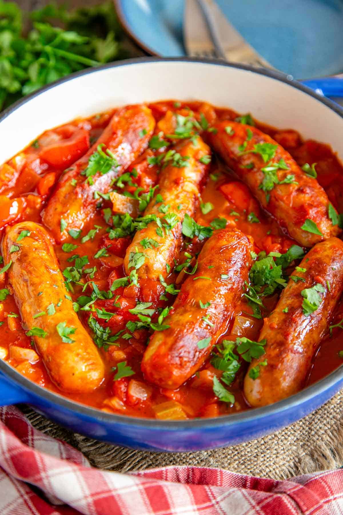 Rich delicious sausage casserole in close up, golden sausage in a rich, thick sauce of tomato, vegetables and bacon.