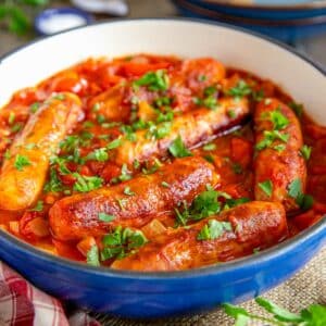 Sausage casserole - delicious traditional sausages in a rich, robust tomato gravy, served up from a cheerful blue casserole dish.