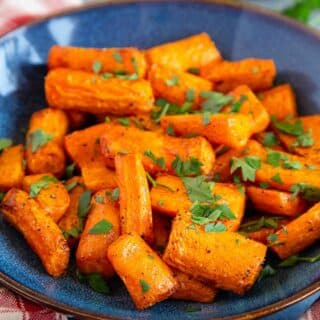 Air fryer carrots garnished with chopped parsley in a blue serving bowl.