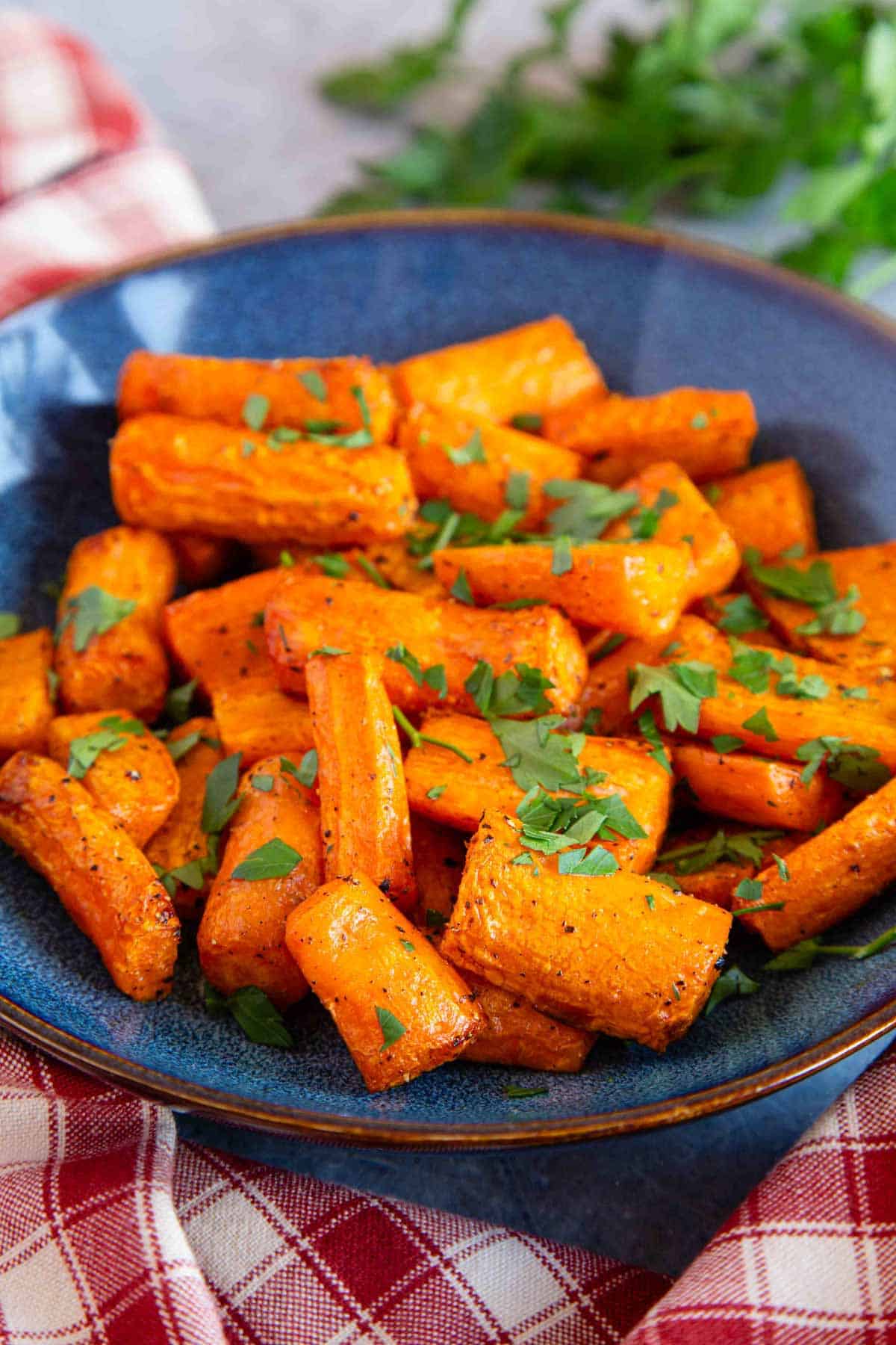 Air fryer carrots garnished with chopped parsley in a blue serving bowl.