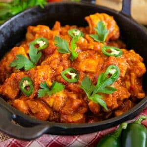 Chicken bhuna, chicken thighs coated in a rich russet sauce, served in a karahi pan.