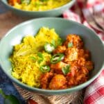 two steaming bowls of chicken dhansak and turmeric rice, garnished with coriander and chilli