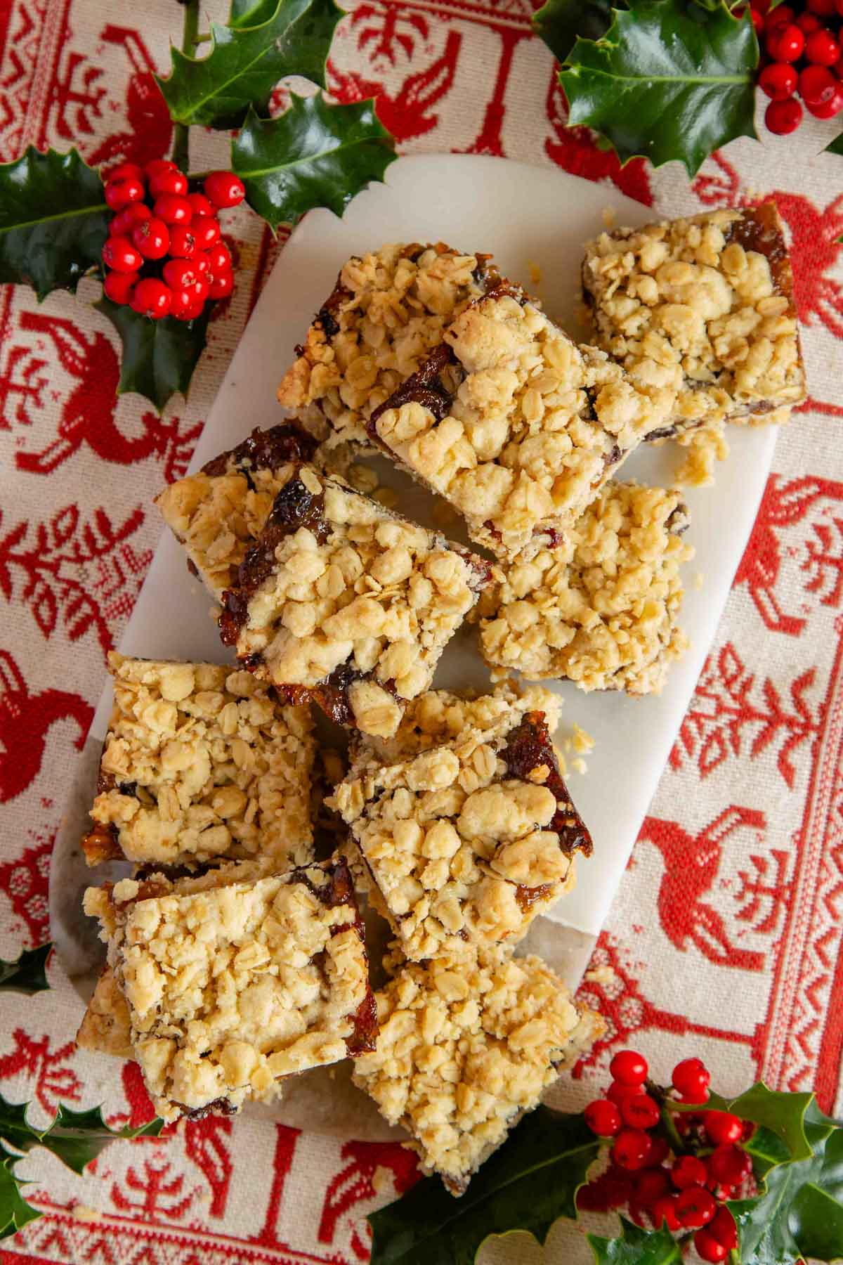 mincemeat crumble bars laid out on a marble board on a festive Scandinavian style embroidered cloth.