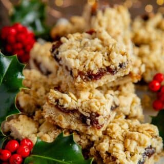meltingly delicious mincemeat crumble bars, piled up on a serving plate, surrounded by Christmas holly