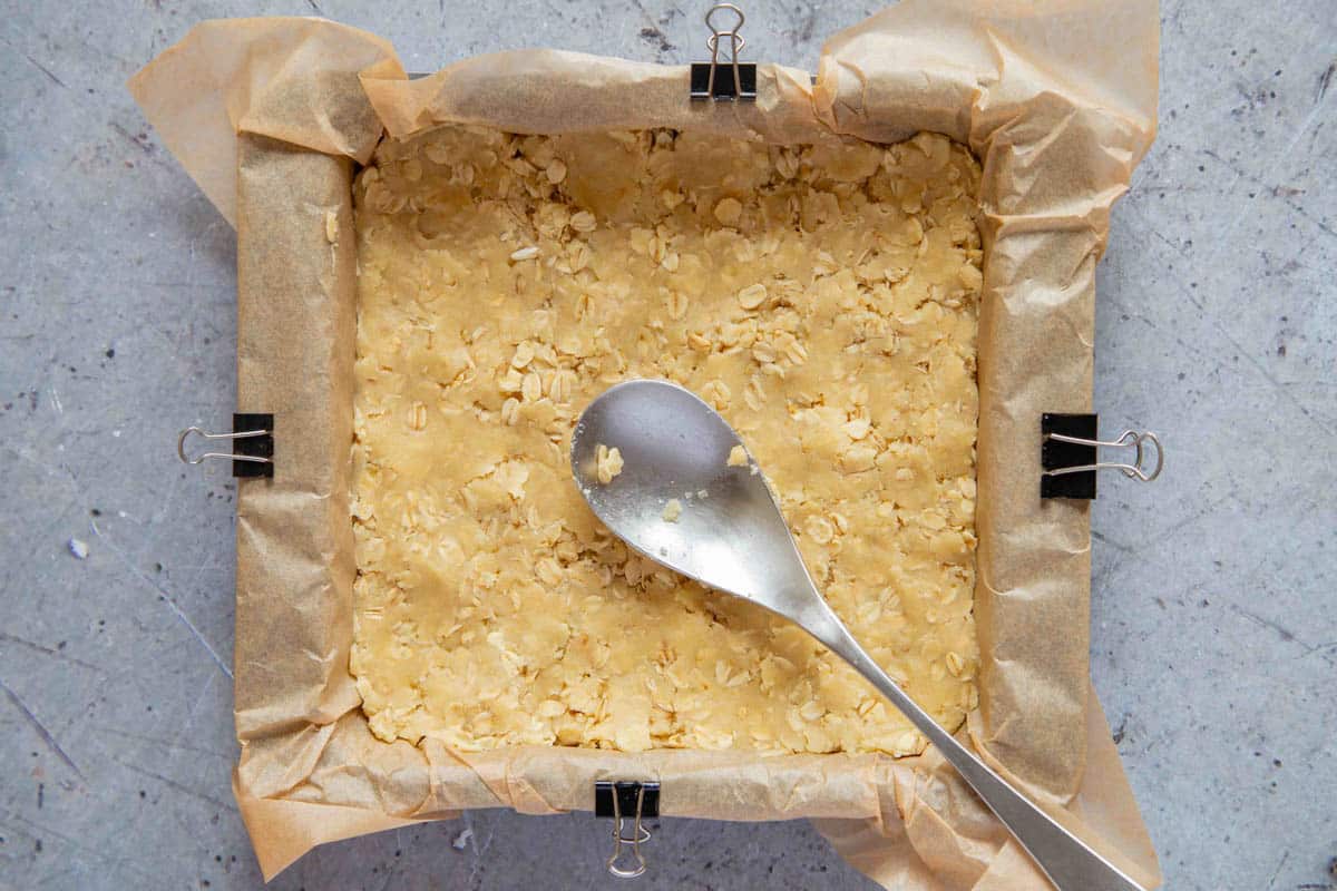 The base formed by pressing crumble mixture into the base of a baking pan.