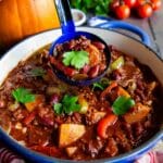 Lifting a spoonful of rich red-brown chilli from the dish.