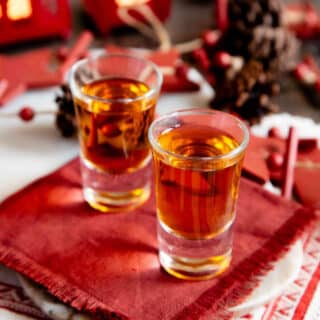 Marmalade gin liqueur served in simple shot glasses against a background of red and white winter decorations.