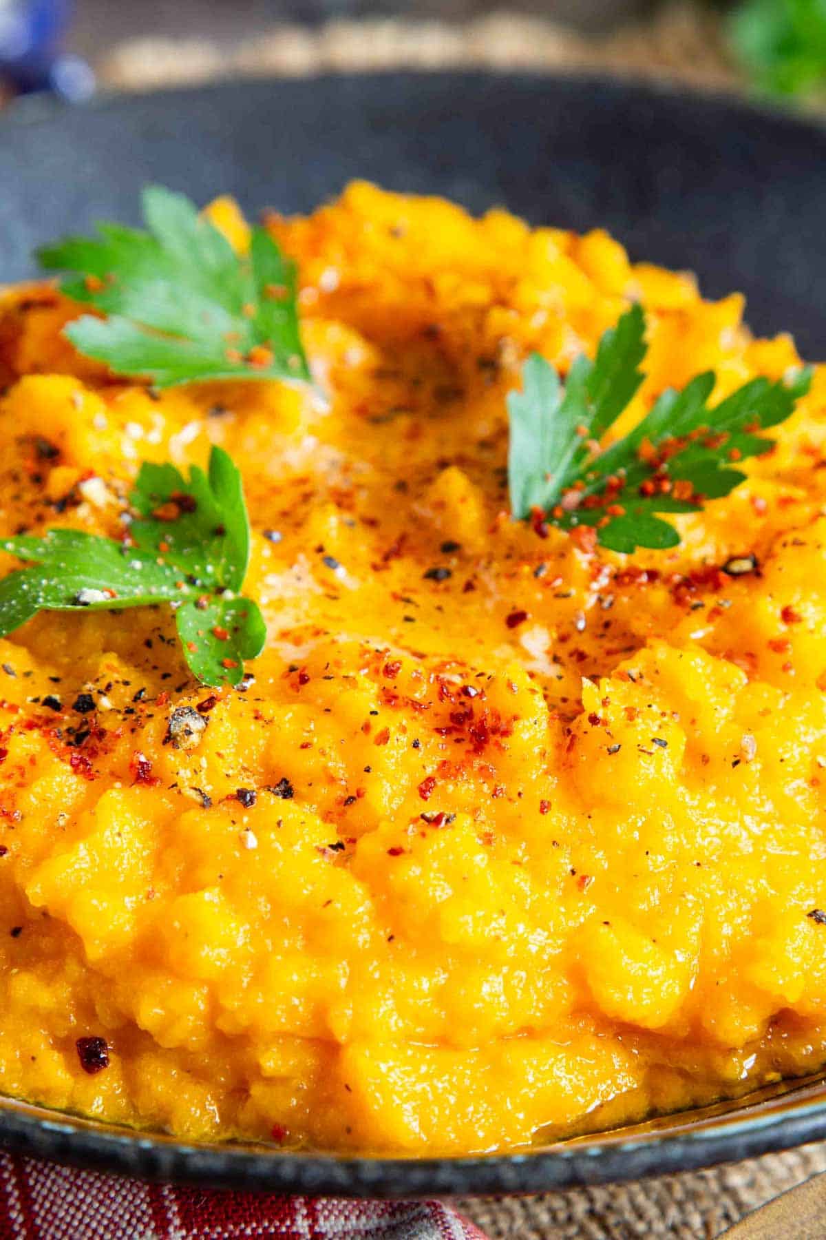 Close up shot of deliciously smooth carrot and swede mash, garnished with parsley and paprika.