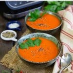 Bright and cheerful orange-red tomato and pepper soup, garnished with fresh parsley.