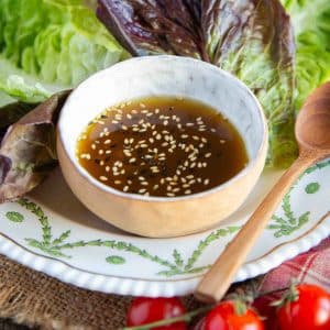 Miso dressing served on the side of a plate of fresh salad leaves in a dainty bowl.