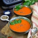 Bright and cheerful orange-red tomato and pepper soup, garnished with fresh parsley.