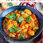 a bowl of freshly cooked chicken jalfrezi garnished with coriander leaves ready to serve with mini naan bread