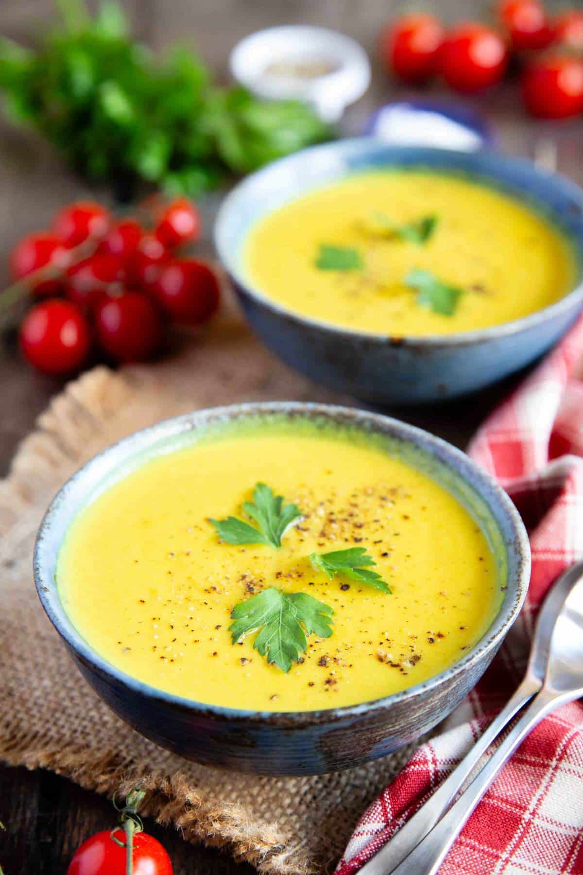 two bowls of pale yellow curried cauliflower soup ready to enjoy