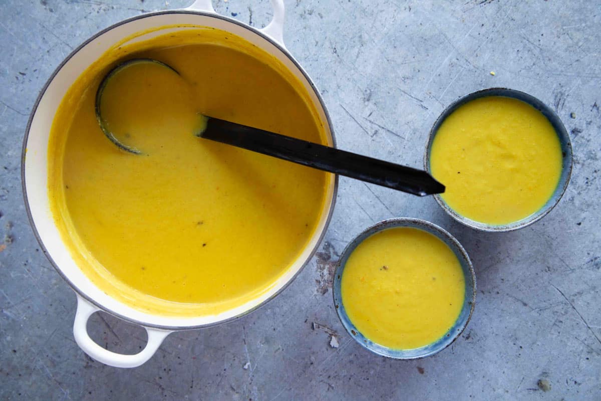 Serving two bowls of hot soup with a ladle