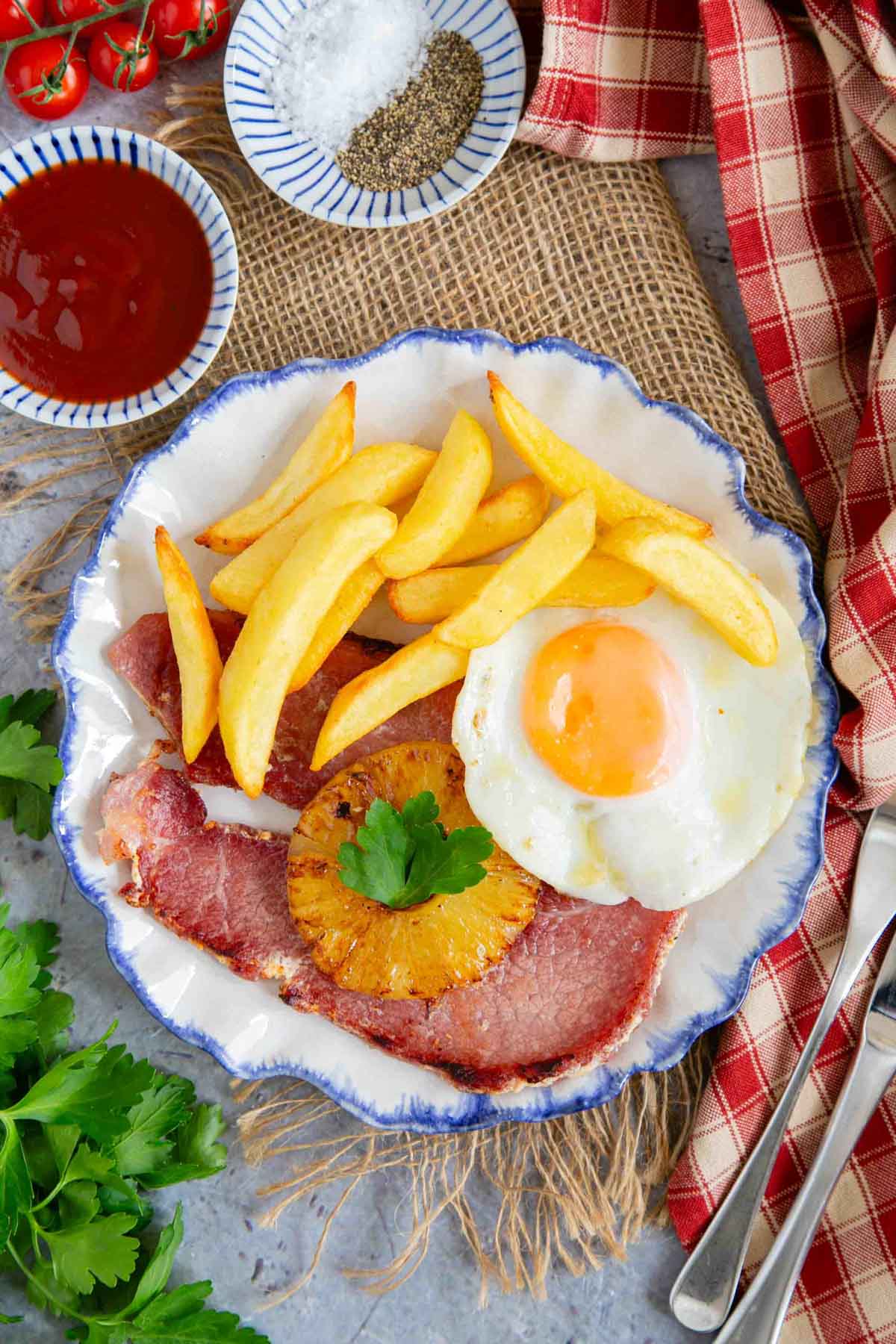 a plate of gammon, egg and chips with a caramelised pineapple ring served and ready to enjoy
