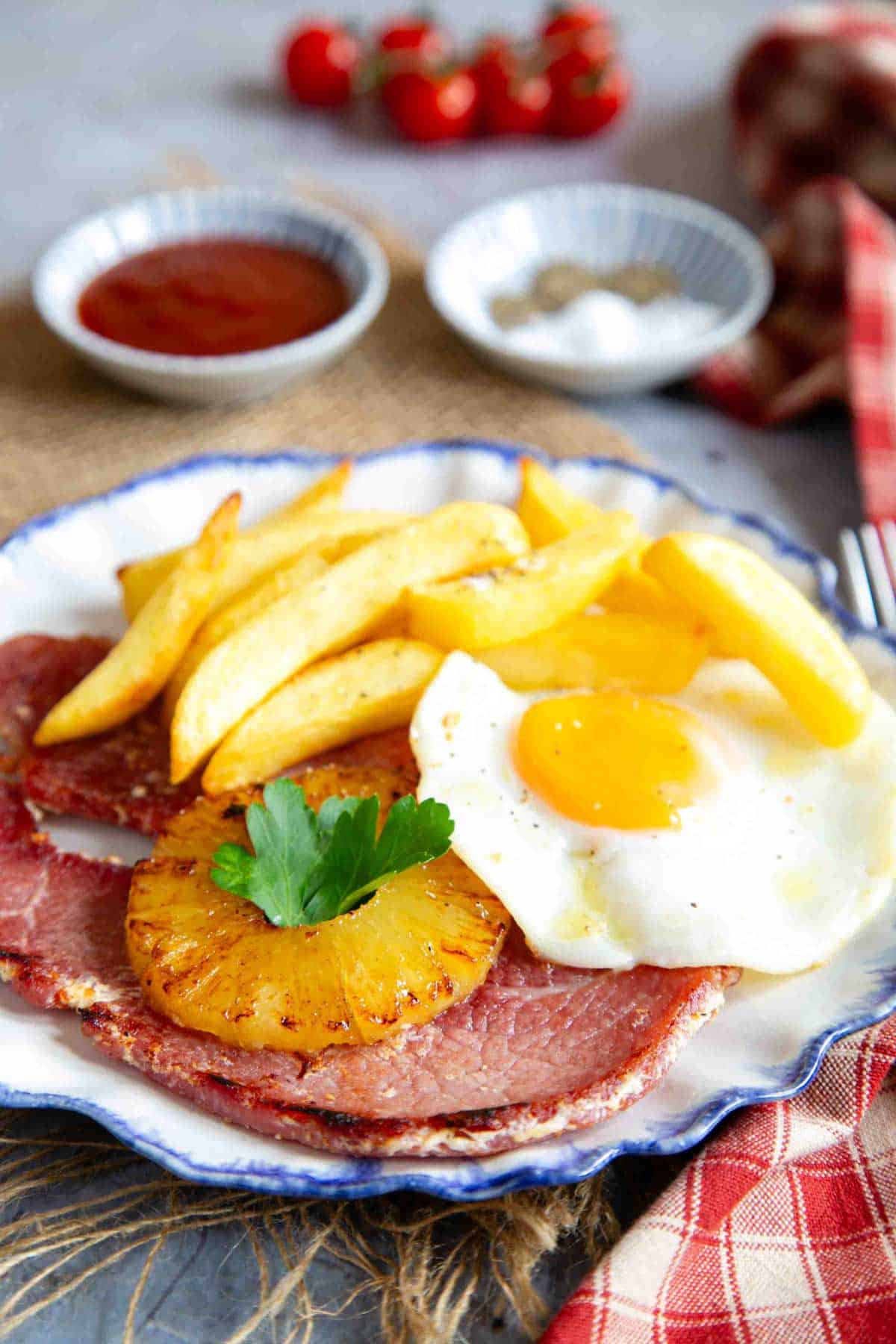 a plate of gammon, egg and chips with a caramelised pineapple ring served and ready to enjoy