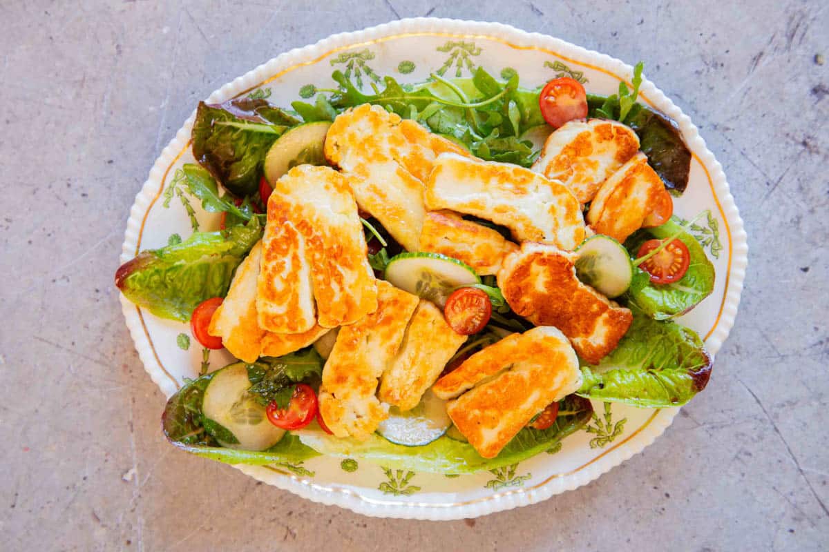 adding the freshly cooked halloumi on top of the salad