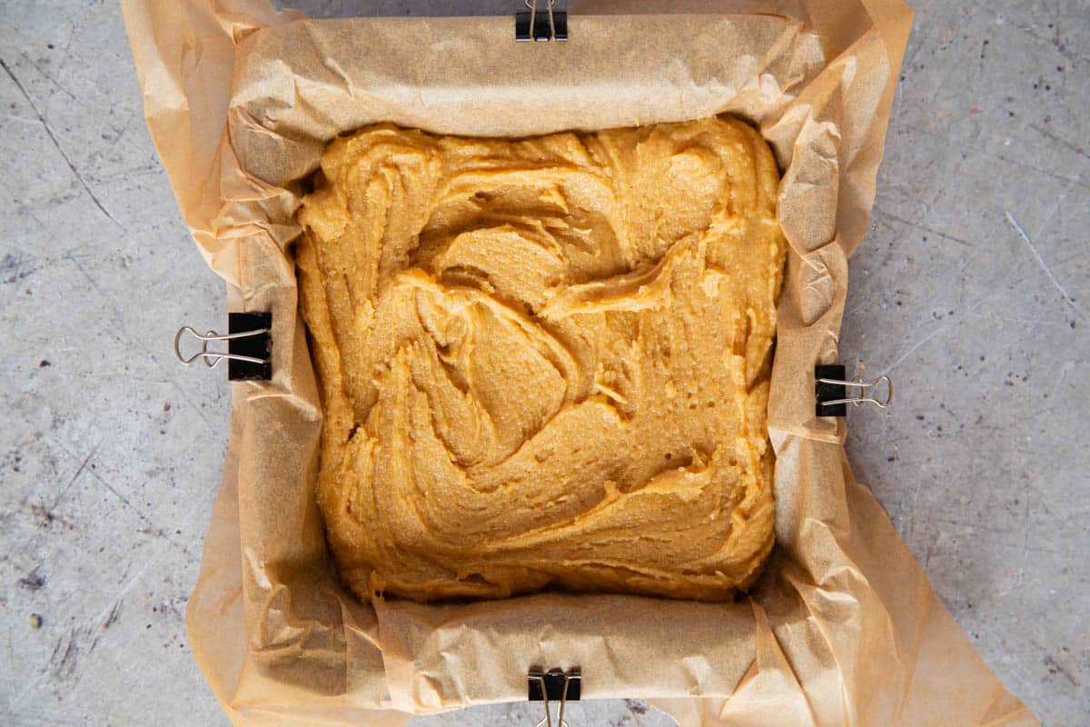 the batter has been spread out in a baking pan lined with parchment paper