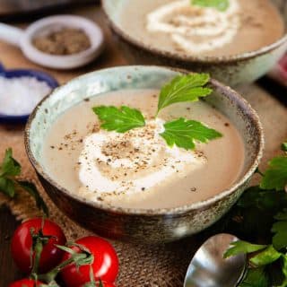 two bowls of freshly made mushroom soup garnished with cream and fresh parsley