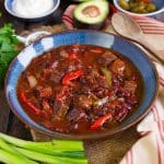 a bowl of freshly cooked chilli con carne surrounded by the traditional chilli toppings
