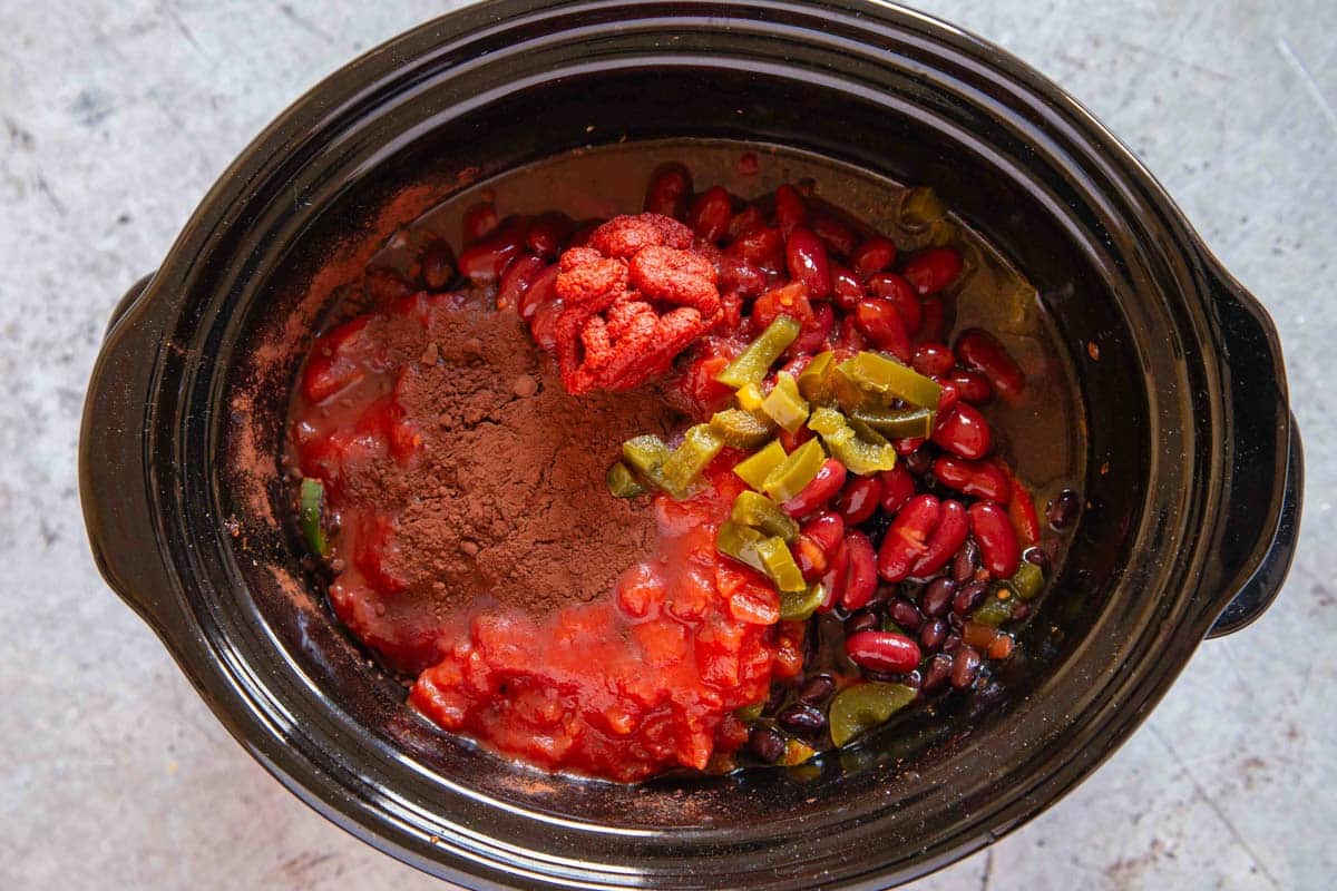 all the ingredients layered into the slow cooker before cooking