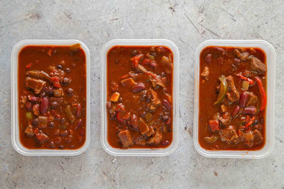 three takeaway trays packed full of leftover chilli ready for the freezer