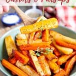 a spoon lifting out a serving of the shiny glazed honey roasted carrots and parsnips from a serving bowl