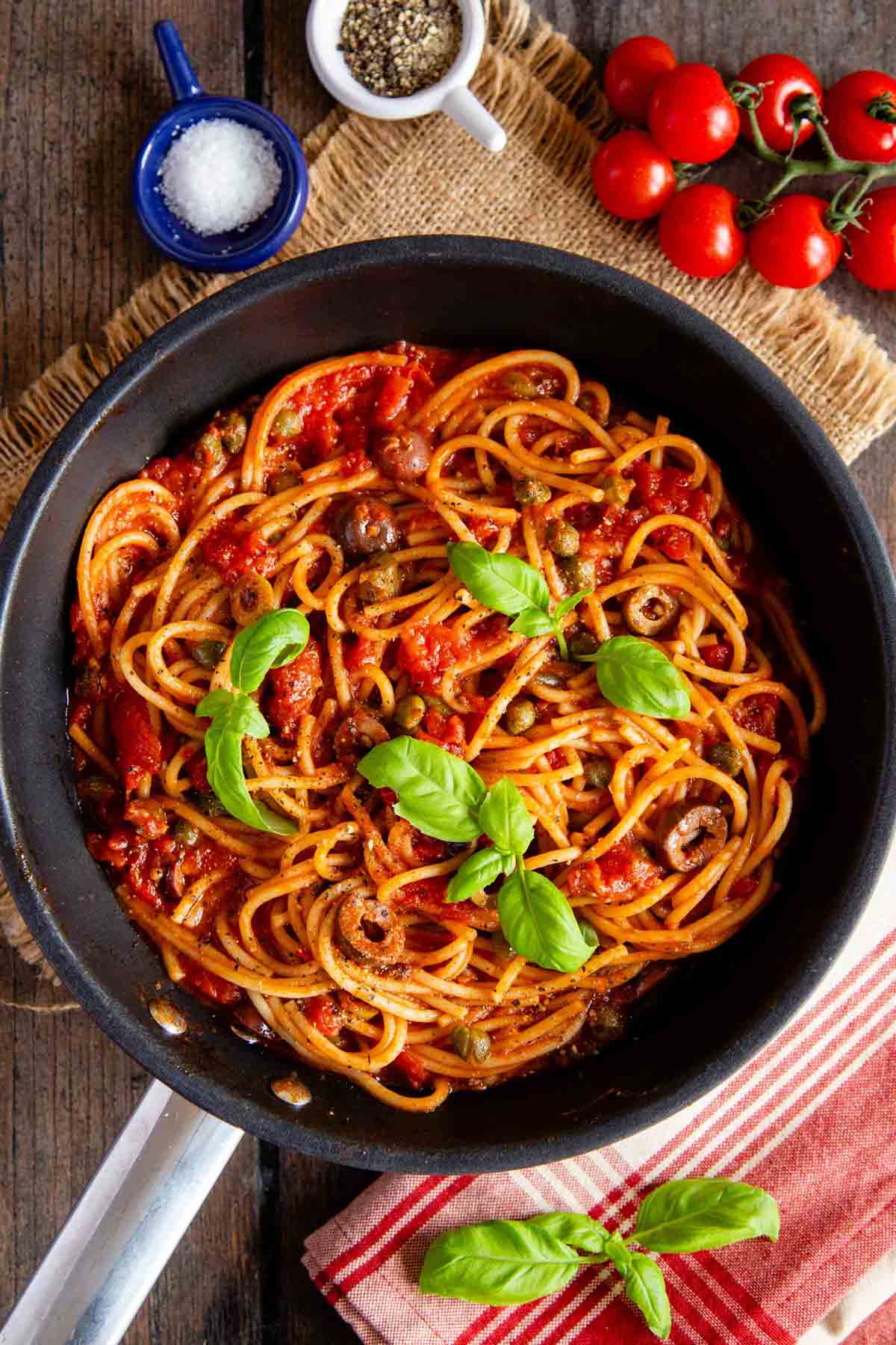 pasta puttanesca in the pan all ready to serve garnished with basil