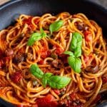 pasta puttanesca in the pan all ready to serve garnished with basil