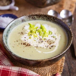 a bowl of freshly made cream of celery soup garnished with extra cream and celery leaves