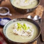 a bowl of freshly made cream of celery soup garnished with extra cream and celery leaves