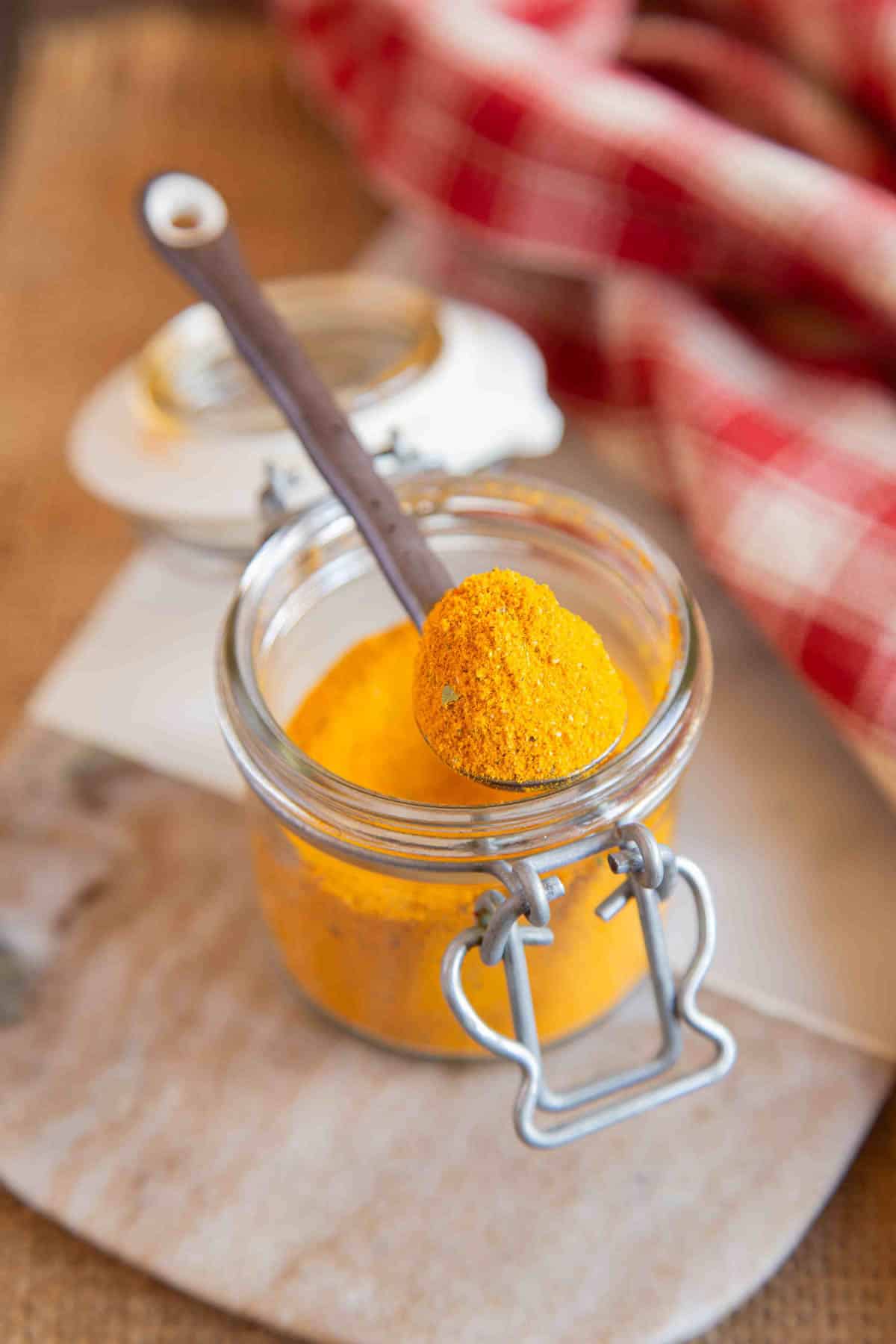 a spoon of golden pilau rice seasoning taken from the jar