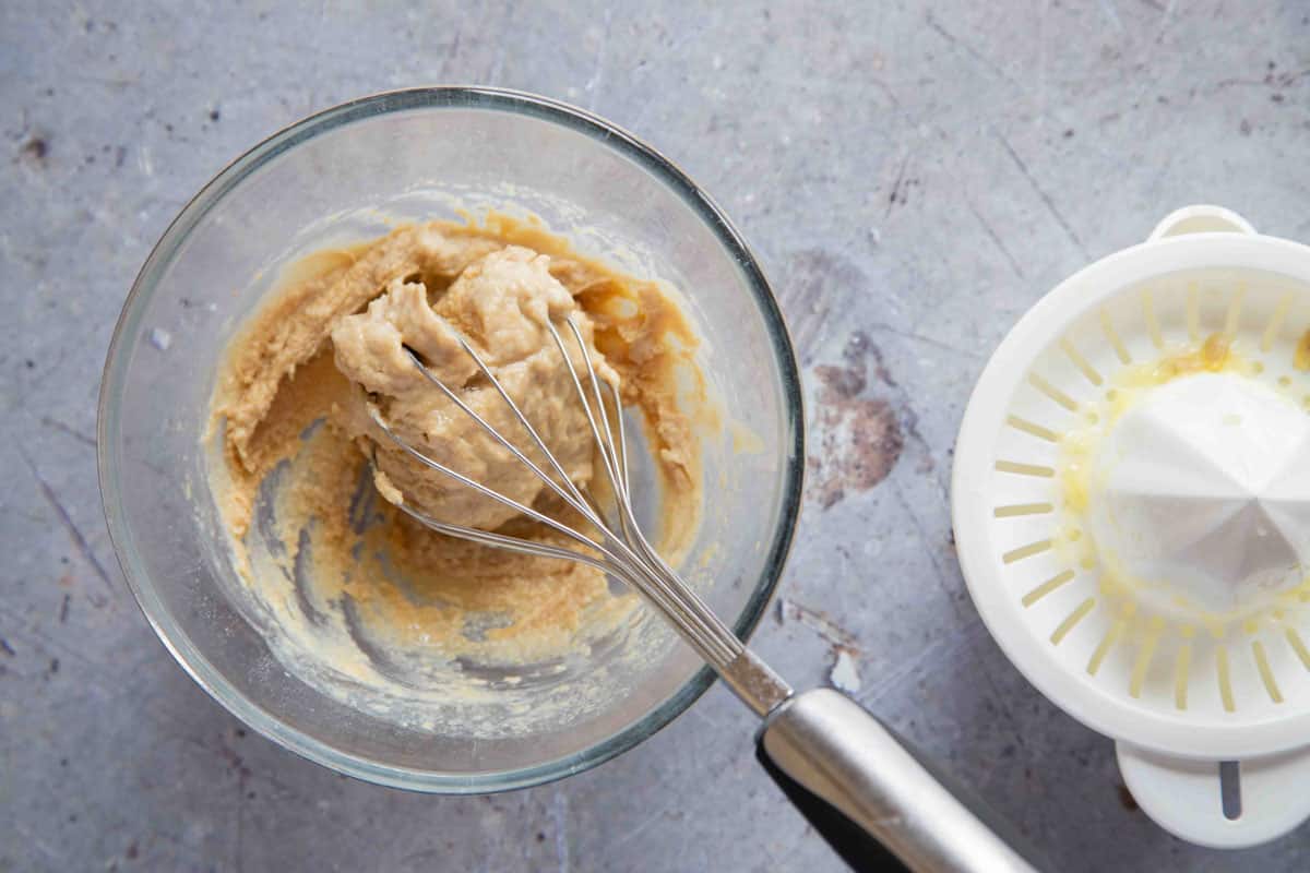 the lemon has been whisked into the tahini which has formed a solid clump around the whisk