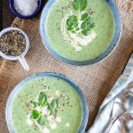 two bowls of pale green watercress soup garnished with a swirl of cream and fresh watercress